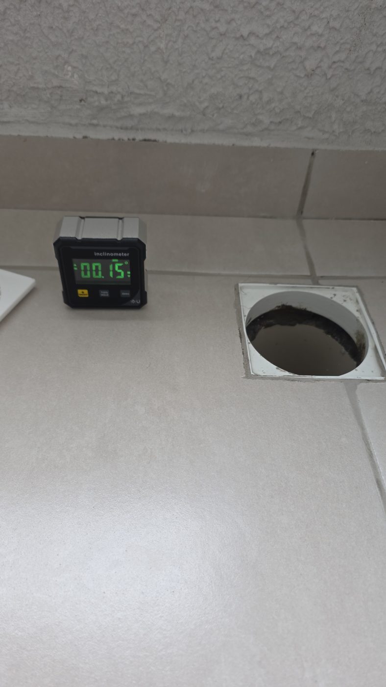 Inclinômetro sobre piso cerâmico ao lado de um ralo